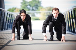 A shot of two business people in a running start position competing against each other
