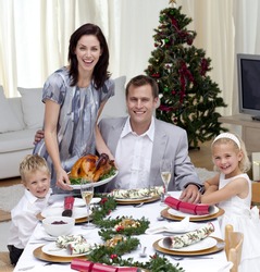 Parents and children celebrating Christmas dinner with turkey at home