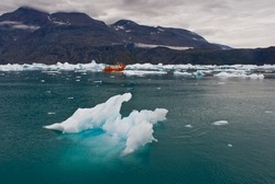 Narsarsuaq Icefjord, Greenland. Iceberg and Icy waters with a small red boat in the background.