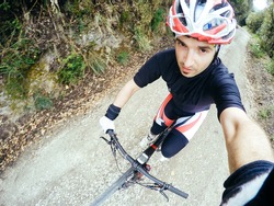 POV, Original point of view. Young man on bicycle take a selfie. Training on mountain bike on a mountainous road.
