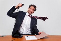 Businessman getting a phone call from an angry person shouting down the line.