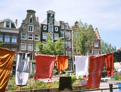 Old houses alongside a canal in Amsterdam. At foreground drying laundry on a houseboat