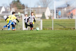 Blur of young kids playing a youth soccer match outdoors on an green soccer pitch.