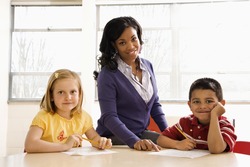 Teacher helping students with schoolwork in school classroom. Horizontally framed shot.