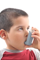 Close up image of a cute little boy using inhaler for asthma. White background vertical studio picture.