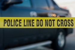 Yellow police tape with text: police line do not cross cornering off area from public access