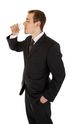 young man in a black business suit holds a glass of water on a white background