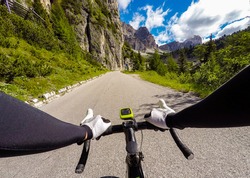 Cyclist on mountainous road in a sunny day. Cycling in Dolomites, Passo Falzarego. POV Original point of view
