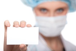 Attractive young female doctor holds a blank card, isolated on white background