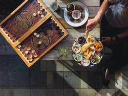 Traditional Lebanese cafe in Beirut: table with backgammon and meze plate and falafel , female hand with pita, view from above