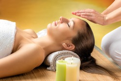 Close up portrait of attractive young woman having alternative treatment therapy. Therapist positioning hands on near forehead.