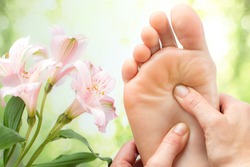 Macro close up of foot massage next to colorful flowers and green background.