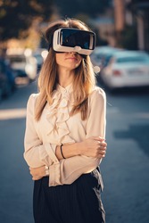 virtual reality headset, virtual reality, VR glasses, augmented reality, VR goggles - happy young girl with virtual reality headset or 360 glasses stay sitting on the street excited by 3D video game