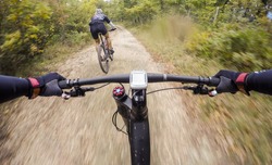 Couple of Cyclists during a mountain bike race in a forest. Drop of water on lens. POV