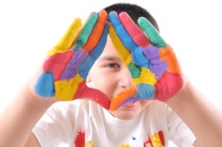 Six year old boy with hands painted in colorful paints ready for hand prints - High resolution, white background, studio image.
