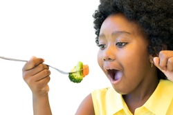 Close up portrait of little african girl taking a bite of broccoli and carrot. Isolated on white.