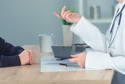 Female doctor explaining situation to patient in hospital office during regular medical exam, healthcare and prevention concept