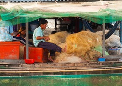 Tonle Sap Lake Siem Reap, Cambodia - OCTOBER 13, 2012: The man and his family weaves a fishing net on the boat house. The life of the local residents