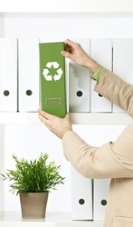 Conceptual image of environmental conservation, businessman holding green folder with recycling symbol.