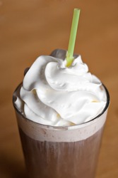 A delicious iced coffee drink topped with fresh whipped cream. Shallow depth of field.