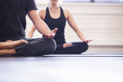 Yoga group concept. Young couple meditating together, sitting back to back on windows background, copy space