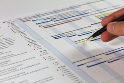 Detailed Gantt Chart showing Tasks, Resources and Notes. Includes a pen being held by a man on the right.