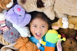 A young girls in the middle of alot of stuffed animals.