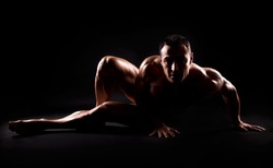 Bodybuilder posing on black background.