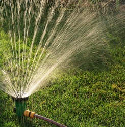 Device of irrigation garden. Irrigation system - technique of watering in the garden. Lawn sprinkler spraying water over green grass.