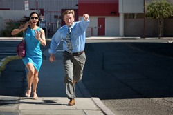 Man and woman run down street to catch taxi.