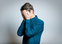 business man crying covering his face, wearing glasses, isolated on a gray background