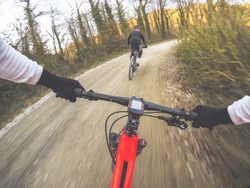 Dramatic shot of pair of young men mountain biking in a forest. POV Original point of view