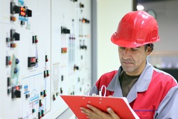 Control Room Engineer. Power plant control panel.
Engineer standing in front of the control panel in the control room and writes the results of measurements.