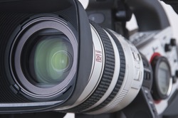 Super close up of Professional Video Camera. The Focus is on the lens and the front part