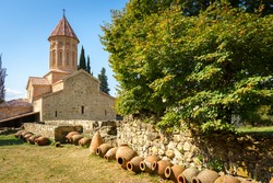 Khvtaeba (Holy Spirit) church at Ikalto monastery and ruins of the academy in Kakheti, Republic of Georgia, Caucasus. Old traditional kvevri wine containers in front.