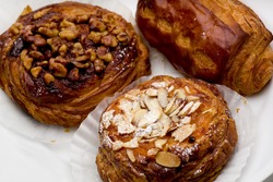 Pain au chocolat, cinnamon walnut, and apricot almond pastries on white plate.