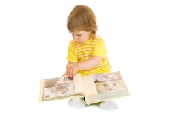 Small girl browsing an family album (faces on the photos cannot be recognized)