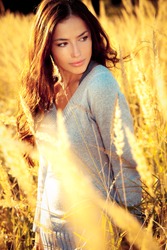 young brunette woman walking through sunny yellow autumn field