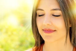 Close up portrait of attractive relaxed young woman meditating outdoors.Girl with eyes closed against bright colorful outdoor background.