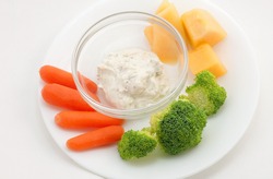 Small veggie plate of baby carrots, broccoli, cantaloupe and garlic dip. White plate on white background. Clean and simple.