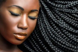 Extreme close up beauty cosmetic portrait of young african woman with eyes closed.Girl wearing professional make up showing black braided hairstyle.
