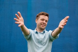 Success positive emotions. Happy young man in blue shirt stretching hands ahead, wanting to hug someone