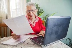 Senior woman calculating her expenses, dissatisfied with the bills and the numbers