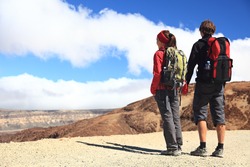 Hiking couple looking at the view holding hands in Teide National Park, Tenerife - Copy space. Image from the volcano on the hiking path to Montana Blanca.