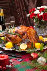 Garnished roast turkey on Christmas-decorated table with candles and flutes of champagne