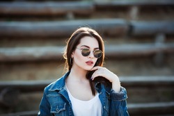 Outdoor fashion closeup portrait of young pretty woman in summer sunny day on street
