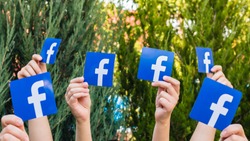 Minsk, Belarus - July, 2017: Concept. Many people. Female. Teenager. Man. Hold the logo of a popular social network Facebook.