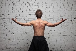 Strong muscular man back at white wall background in flying and free standing