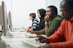 Multiethnic computer class with indian, middle eastern, hispanic and caucasian people training with pc. Horizontal shape, side view, waist up