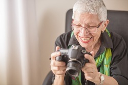 Happy senior old woman reviewing photos on the back of her DSLR camera LCD screen